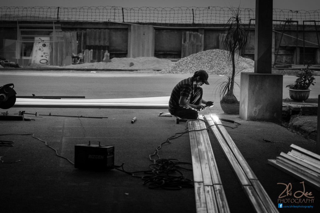 A welder in Hanoi uses his hands as a screen. By Zhi Lee